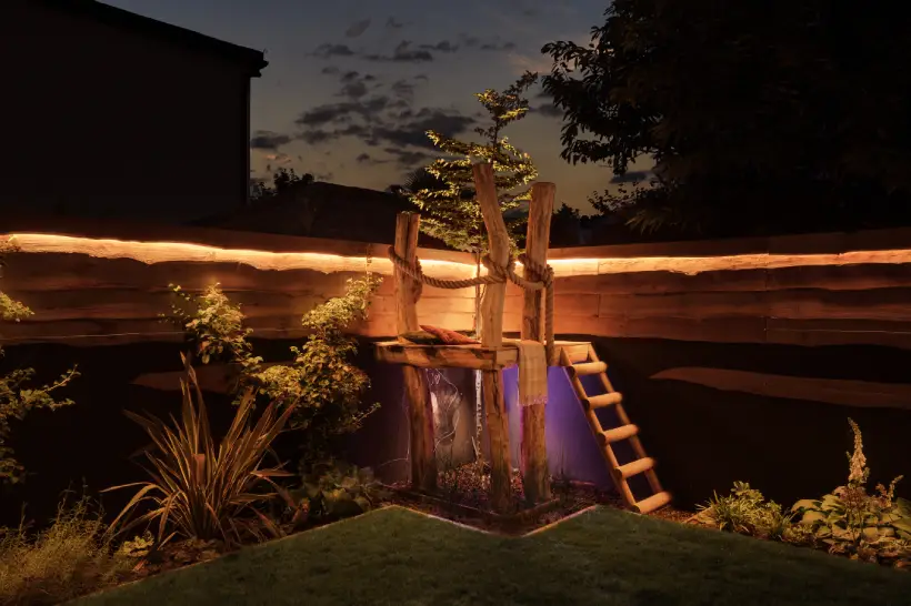 children's seating area in a garden, lit up at night with surrounded lights and a purple light underneath